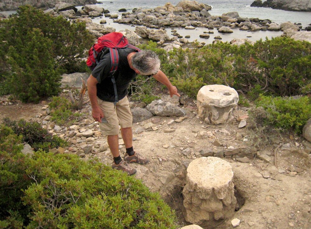 Escursionista osserva capitelli antichi sulla costa rocciosa - Grecia