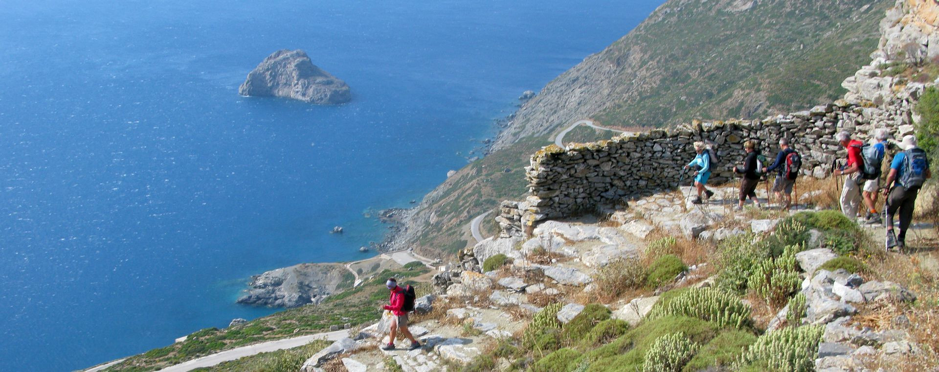 Randonneurs sur un sentier dallé au-dessus de la mer - Amorgos - Cyclades